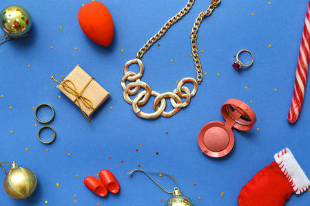 Christmas composition with jewelry, cosmetic and decor on blue background
