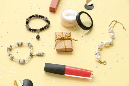 Christmas composition with makeup cosmetics, jewelry and confetti on yellow backgroundの写真素材