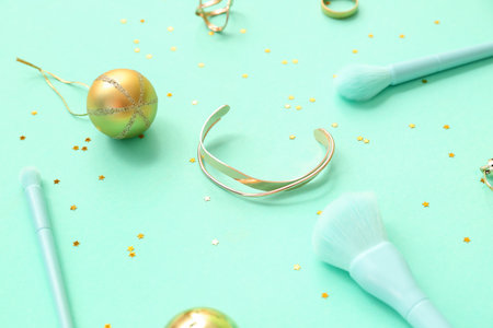 Christmas composition with makeup brushes, jewelry and decor on turquoise backgroundの写真素材