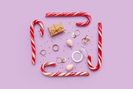 Christmas composition with makeup cosmetic, jewelry and candy canes on lilac backgroundの写真素材