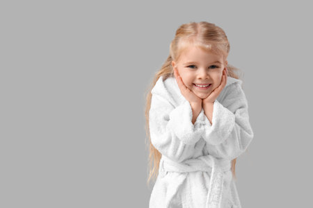 Cute little girl in bathrobe on light backgroundの写真素材