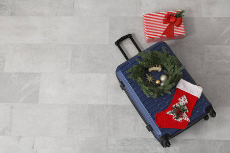 Suitcase with Christmas wreath, sock and gift on gray tile floor, top viewの写真素材