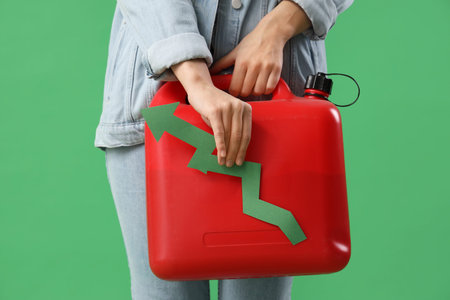 Young woman with plastic jerrycan and arrow on green background, closeup. Price rise concept