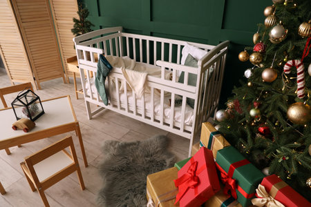 Interior of cozy nursery room with crib, Christmas tree and giftsの写真素材