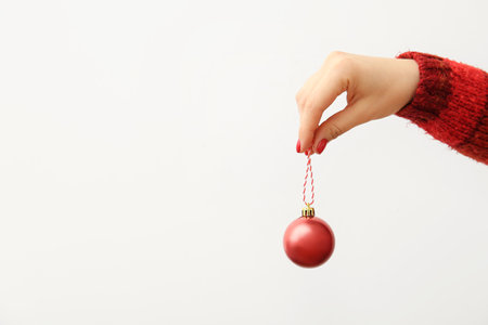Female hand with red manicure holding Christmas ball on white background, closeupの写真素材