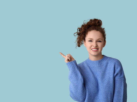 Portrait of ashamed young woman pointing at something on blue backgroundの写真素材