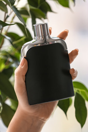 Female hand with bottle of elegant perfume near windowの写真素材