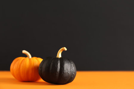 Painted pumpkins on orange table near black wallの写真素材