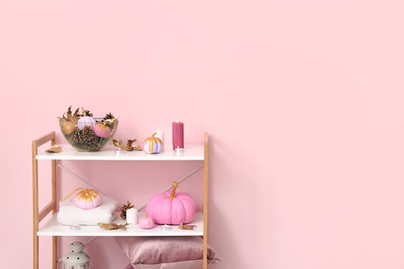 Painted pumpkins with beautiful decorations and burning candles on shelving unit in roomの写真素材