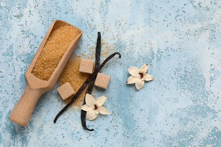 Scoop with aromatic vanilla sugar, flowers and sticks on blue backgroundの写真素材