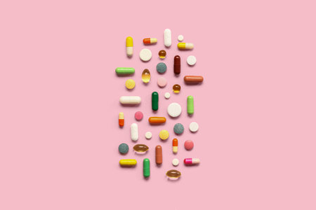 Fish oil capsules and different pills on pink backgroundの写真素材