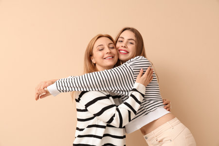 Happy young woman hugging her mother on beige background. International Hug Dayの写真素材