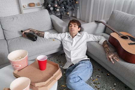 Drunk young man sleeping after New Year party at homeの写真素材