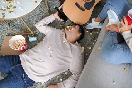 Drunk young man sleeping on floor after New Year party at home, top viewの写真素材