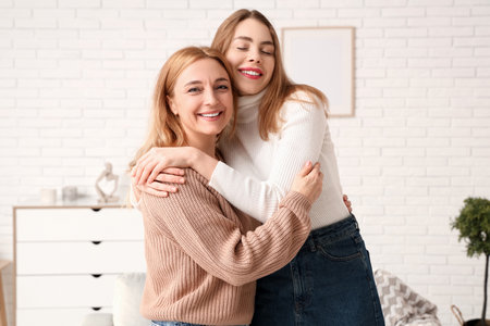 Happy young woman hugging her mother at home. International Hug Dayの写真素材