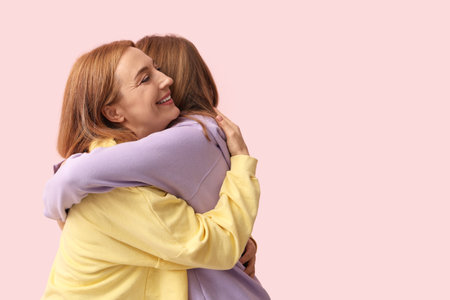 Beautiful young woman hugging her mother on pink background. International Hug Dayの写真素材