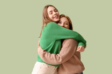 Happy young woman hugging her mother on green background. International Hug Dayの写真素材