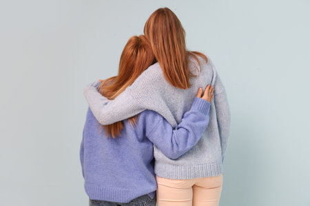 Young woman hugging her mother on blue background. International Hug Dayの写真素材