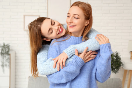 Happy young woman hugging her mother at home. International Hug Dayの写真素材