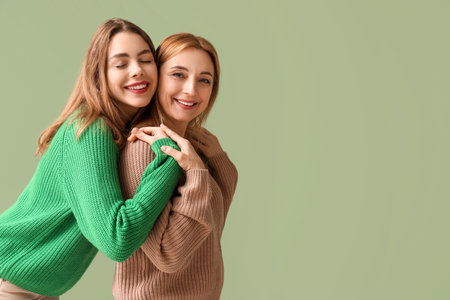 Happy young woman hugging her mother on green background. International Hug Dayの写真素材