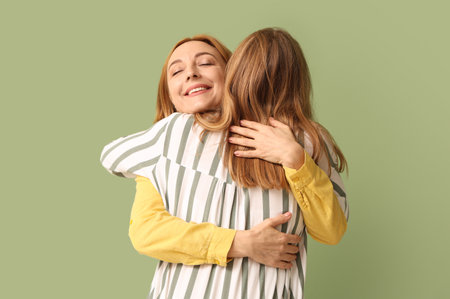 Mature woman hugging her young daughter on green background. International Hug Dayの写真素材