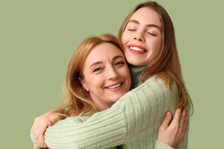 Happy young woman hugging her mother on green background. International Hug Dayの写真素材