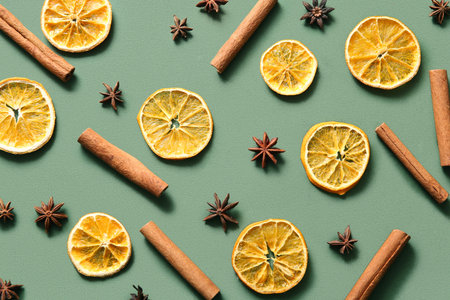 Dried orange slices with cinnamon and star anise on green background