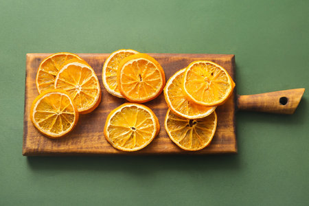Wooden board with dried orange slices on green backgroundの写真素材