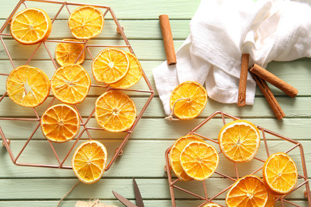Stands with dried orange slices and cinnamon on green wooden background