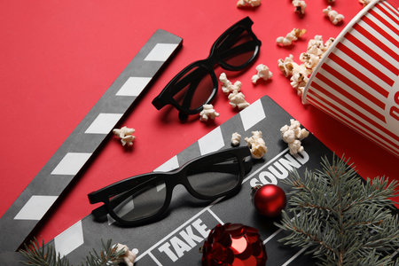 Bucket of popcorn with movie clapper, 3D glasses and Christmas decor on red backgroundの写真素材