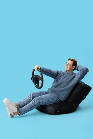 Young man with steering wheel on blue background