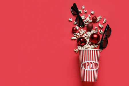 Bucket of popcorn with 3D glasses and Christmas tree balls on red backgroundの写真素材