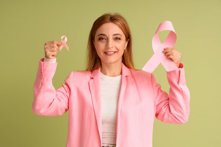 Mature woman with pink ribbons on green background. Breast cancer awareness conceptの写真素材