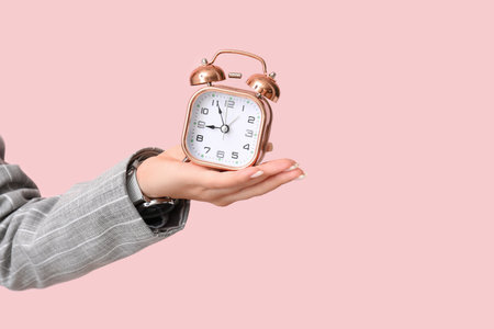 Female hand with alarm clock on pink background. Time management conceptの写真素材