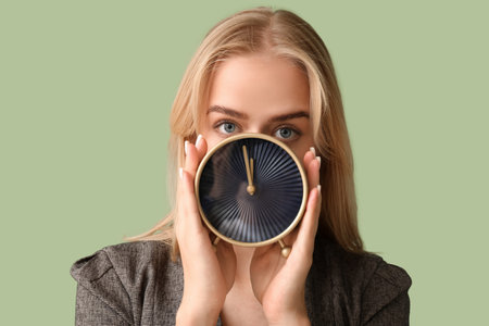 Young businesswoman with alarm clock on green background. Time management concept
