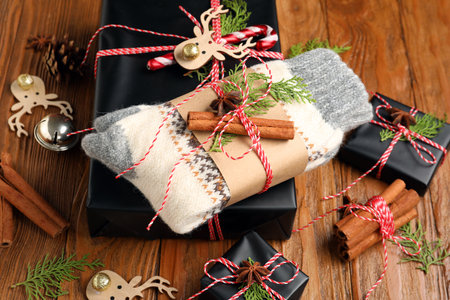 Knitted socks with Christmas gift boxes and different spices on wooden backgroundの写真素材