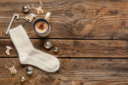 Knitted socks with Christmas decorations and cup of coffee on wooden backgroundの写真素材