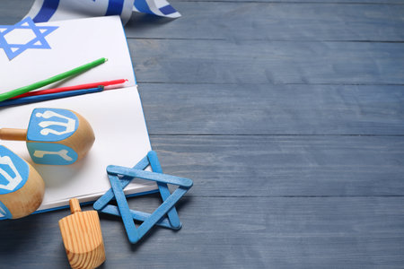 Hanukkah composition with open book, dreidels, David star and candles on blue wooden backgroundの写真素材