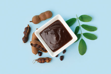 Bowl with tasty tamarind jam and fruits on blue backgroundの写真素材