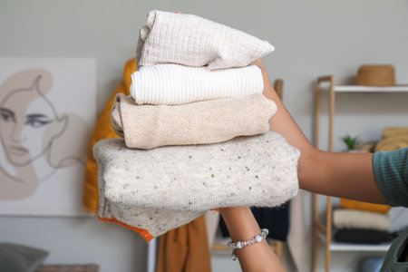 Woman with stack of clean clothes in laundry room, closeup