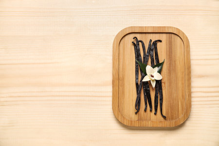 Board with aromatic vanilla sticks and flower on wooden backgroundの写真素材
