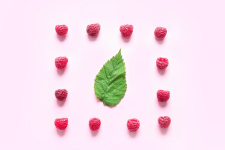 Fresh ripe raspberries and leaves on pink background