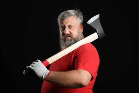 Portrait of mature lumberjack with ax on black backgroundの写真素材