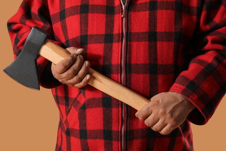 Man in red plaid shirt holding ax on beige backgroundの写真素材