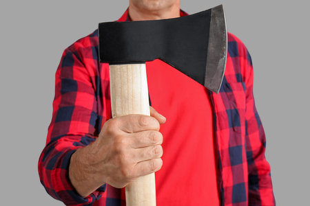 Man in red plaid shirt with ax on gray backgroundの写真素材