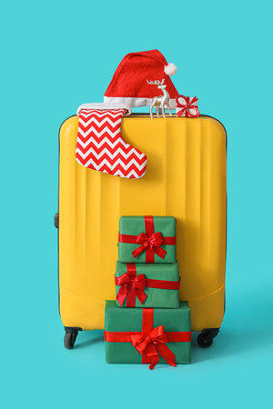 Suitcase with Santa hat, Christmas sock and presents on blue backgroundの写真素材