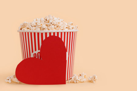 Bucket of popcorn and paper heart on yellow background. Valentine's Day celebrationの写真素材