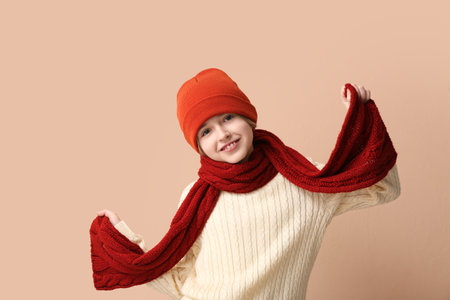 Cute little happy boy in winter clothes on beige backgroundの写真素材