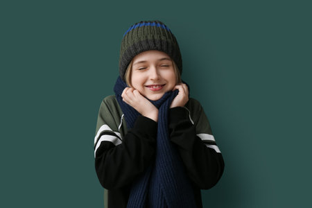 Cute little boy in winter clothes on dark green background