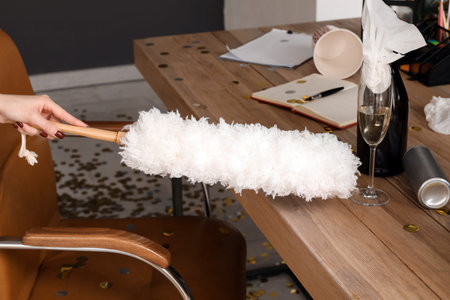 Janitor cleaning table in messy office after New Year party, closeup